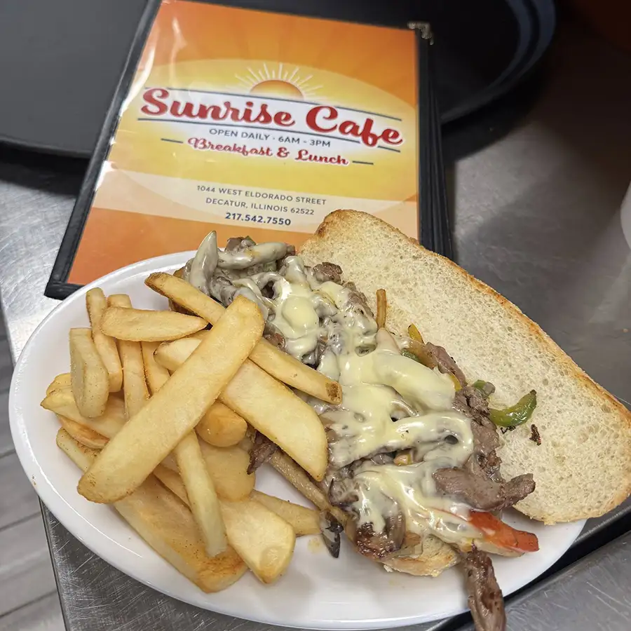 Sunrise Cafe menu next to plate of classic philly cheese steak sandwich from the lunch menu in Decatur, IL